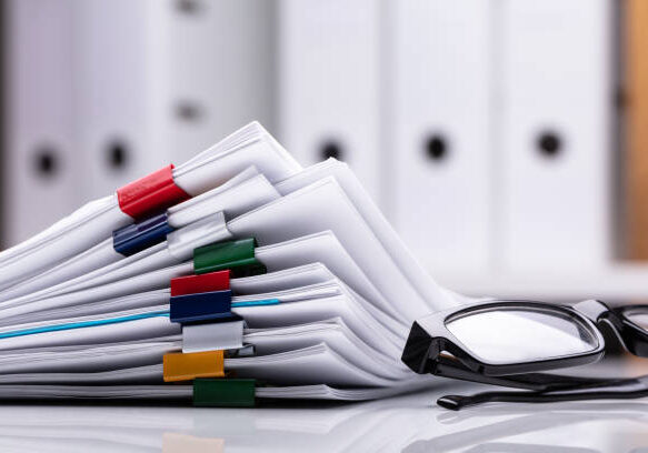 Stacked Documents With Colorful Paperclips And Eyeglasses